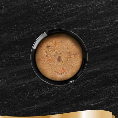 Cuenco negro con comida húmeda compuesta de ingredientes troceados en una textura cremosa.