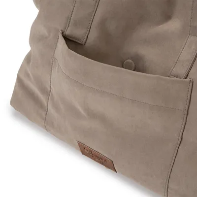 Gros plan sur une poche extérieure d’un sac en tissu beige avec étiquette marron portant l’inscription « Aquadog Home ». Bouton pression visible sur la poche.