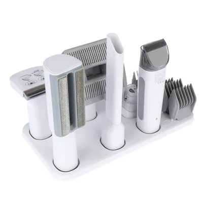 White grooming set with various attachments, including brushes, comb attachments and trimmer, arranged on a stand.