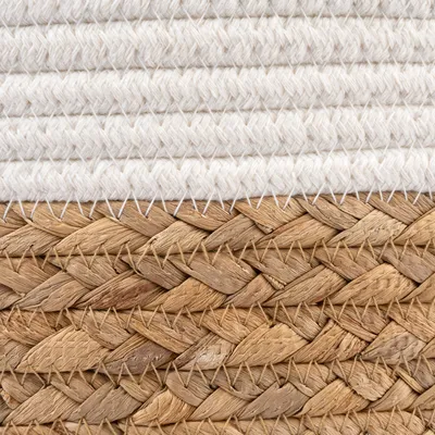 Detailní záběr produktu z přírodního pleteného materiálu v hnědé barvě a bílá látka s hrubou strukturou.