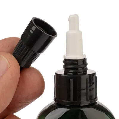 Nahaufnahme einer schwarzen Flasche mit abnehmbarem Deckel und weissem Dosieraufsatz, geeignet für präzise Anwendung von Flüssigkeiten.