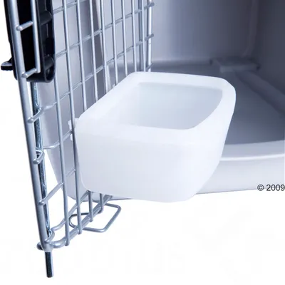 White plastic drinking bowl attached to a metal grid of a transport box.