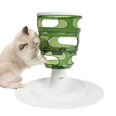 Katze interagiert mit grünem Futterturm von Catit, der mehrere Ebenen und Öffnungen für spielerisches Fressen bietet.