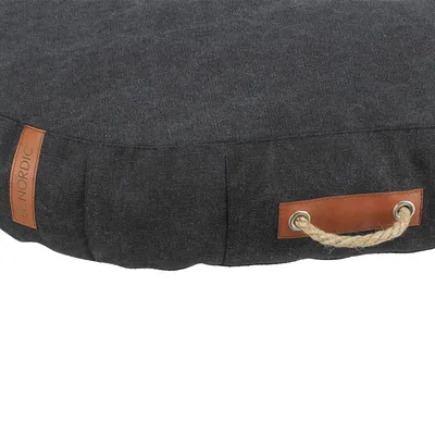 Rundes dunkelgraues Kissen mit braunen Lederdetails und Griff aus Seil. Label mit Aufschrift 'NORDIC' sichtbar.