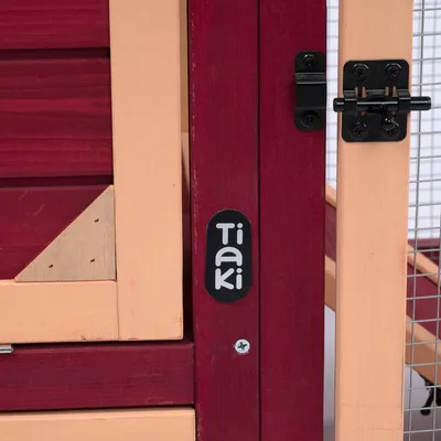 Tiaki logo na červenom a béžovom dreve s čiernym kovovým uzáverom a mriežkovými prvkami.