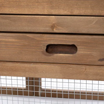 Detailný pohľad na drevenú rukoväť zásuvky s kovovou mriežkou pod ňou. Materiál: drevo a kov.
