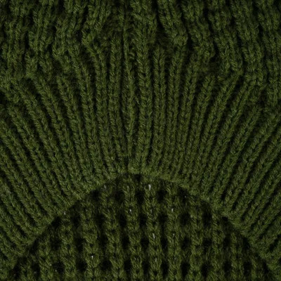 Gros plan sur un tricot vert en maille épaisse, motif côtelé et ajouré, matière textile visible.