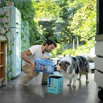 Un homme tient un paquet 'Edgard & Cooper Sunday Chicken' de croquettes, un chien le renifle. Boîte bleue avec texte 'Être en forme' à côté.