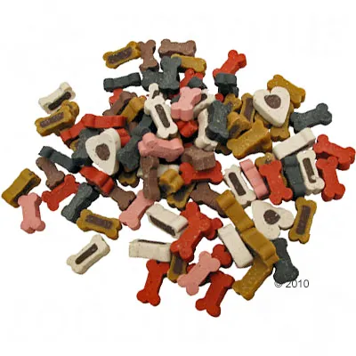 Blandning av små hundgodisbitar i form av ben och hjärtan i olika färger, inklusive rött, vitt, brunt, rosa, gult och svart. Ingen synlig förpackning eller text.