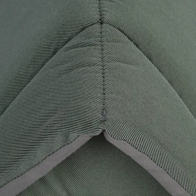 Primer plano de material textil verde con fina estructura de rayas y costura visible.