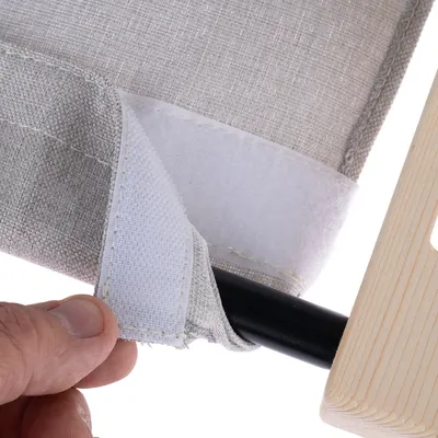 Närbild av ett kardborrband på ett grått tygöverdrag som fästs runt en svart metallstång och en trädel.