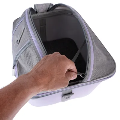 Sac de transport gris à mailles avec fermeture éclair, intérieur rembourré noir et attache métallique, main tenant l’attache à l’intérieur du sac.