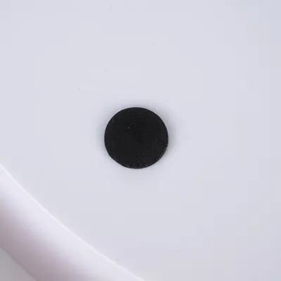Black round felt glider on white surface, suitable for furniture or flooring.
