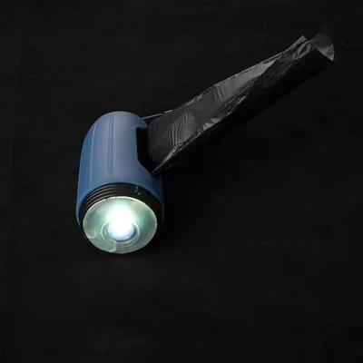 Blauer Taschenlampenhalter mit integrierter Spenderfunktion für schwarze Müllbeutel, leuchtendes Licht sichtbar.