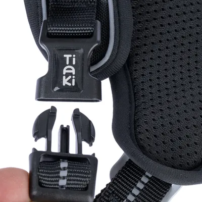 Nahaufnahme eines schwarzen Klickverschlusses mit Tiaki-Logo, befestigt an einem atmungsaktiven, gepolsterten Material.