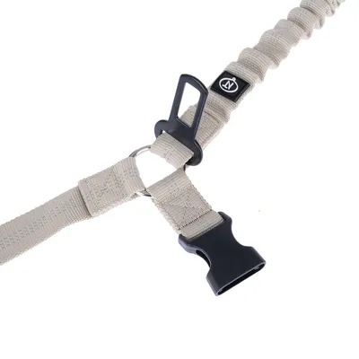 Sangle beige en tissu avec boucle de sécurité noire, mousqueton métallique et attache pour ceinture de voiture, logo visible sur l’étiquette cousue.