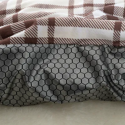 Közelkép egy barna-fehér kockás szövetről, csúszásgátló fekete méhsejt mintás alsó résszel.