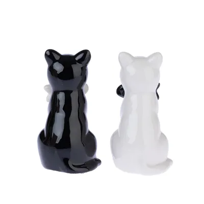 Deux figurines en céramique en forme de chat, une noire et une blanche, avec surface brillante. Vue arrière des figurines.