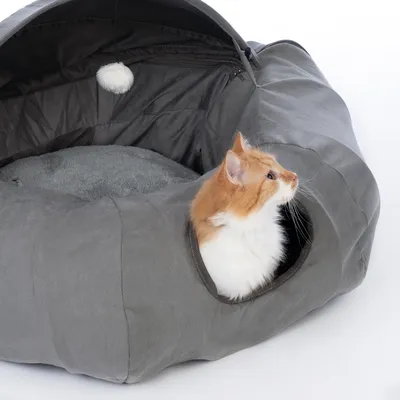 Grey cat bed with cave design, soft inner padding and hanging toy. Cat looking out from the entrance.