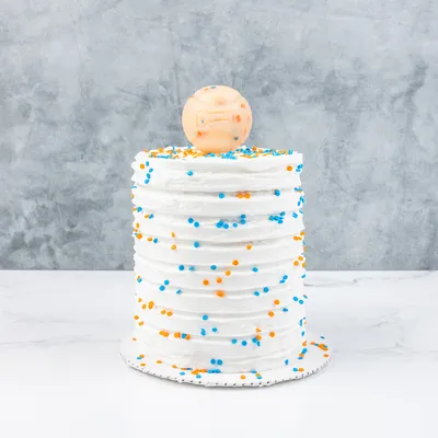 Torta bianca con granelli blu e arancioni, decorata con una palla sopra. Nessuna informazione aggiuntiva visibile.