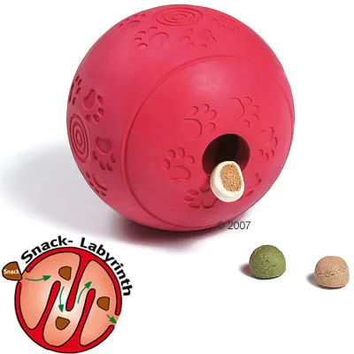 Balle rouge en caoutchouc avec empreintes de pattes, trou pour friandises, deux croquettes à côté. Schéma Snack-Labyrinth montrant le parcours des friandises à l’intérieur.