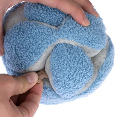 Handen drukken op een blauwe pluchen bal om een verborgen snack te onthullen.