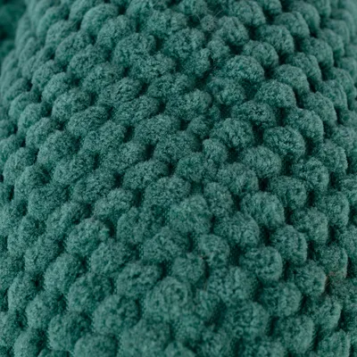 Gros plan sur une surface en tissu tricoté vert, texture bouclée visible. Matériau textile uniquement, aucun autre élément identifiable.