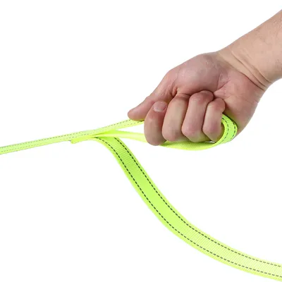 Hand håller ett neon-gult hundkoppel med svarta sömmar, lämpligt för stadigt grepp och kontroll.