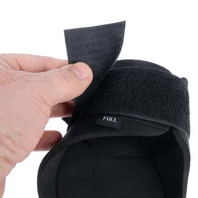 Nahaufnahme eines schwarzen Produkts mit Klettverschluss, der geöffnet wird. Etikett mit Aufschrift 'FULL' sichtbar.