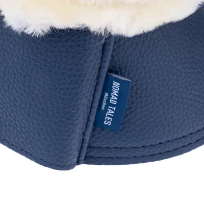 Étiquette bleue avec texte visible : NOMAD TALES München, cousu sur un article en similicuir bleu et doublure en tissu peluche blanc.
