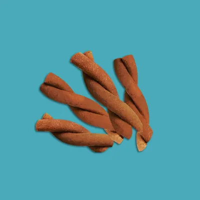 Mehrere gedrehte braune Kausnacks auf blauem Hintergrund, sichtbar ohne Verpackung.