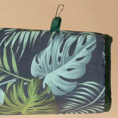 Hamaca con diseño de hojas tropicales, borde verde oscuro y ganchos metálicos para fijación.