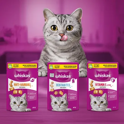 Tri vrečke Whiskas priboljškov za mačke: Anti-Hairball mit Huhn 50 g, Dentabites mit Huhn 40 g, Vitamin E-Xtra mit Huhn 50 g. Na embalaži piše 'weniger Plastik', 'neue Verpackung'.