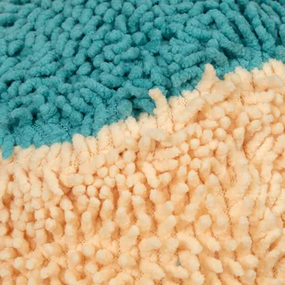 Nærbillede af et tofarvet tæppemateriale med turkis og beige fibre.