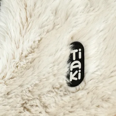 Tiaki-logo op wit, pluizig materiaal.