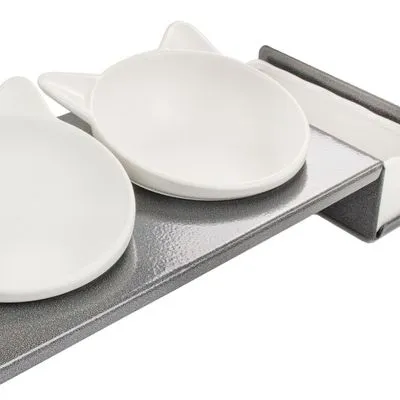 Twee witte keramische voerbakken in kattenvorm op een grijze standaard, geschikt voor huisdieren. Materiaal: keramiek en metaal.