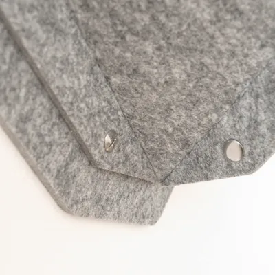 Graue Filzmaterialien mit silbernen Druckknöpfen, geeignet für handwerkliche oder dekorative Anwendungen.