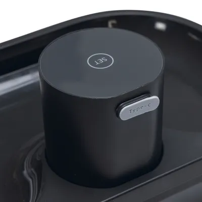 Bouton rond noir avec inscription « SET » et port marqué « Type-c » sur un appareil en plastique noir.