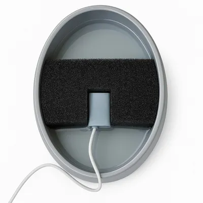 Oval vattenbehållare med svart skumfilter och vit strömkabel, filterinsats synlig. Oval vattenbehållare med svart skumfilter och vit strömkabel, filterinsats synlig.