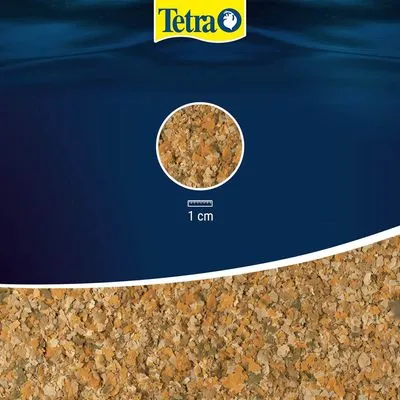 Tetra vlokkenvoer, detailopname van de vlokkenstructuur met schaal: 1 cm. Merknaam Tetra zichtbaar bovenaan.