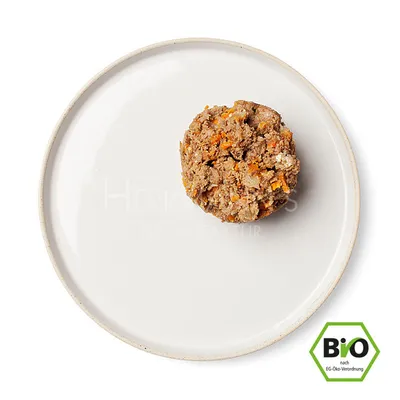 Portion vådfoder med synlige grøntsagsstykker på hvid tallerken, tekst 'Herrmann's Manufaktur' og mærket 'BIO nach EG-Öko-Verordnung' nederst til højre.