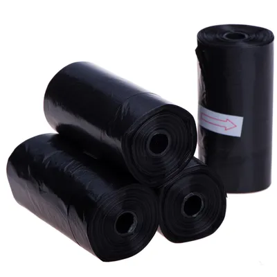 Vier rollen zwarte plastic zakjes, één rol met een witte sticker en rode pijl zichtbaar. Geen merknaam of extra tekst aanwezig.