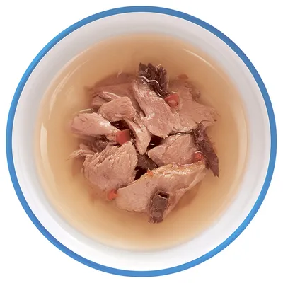 Кусочки мяса в соусе в белой миске с синей окантовкой, вид сверху. Видны небольшие кусочки овощей.