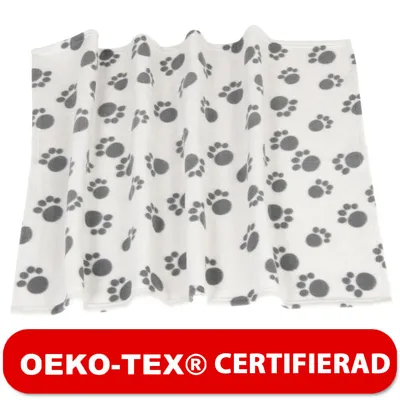 Vit filt i tyg med grå tassavtryck, OEKO-TEX® CERTIFIERAD står på röd banderoll längst ner.