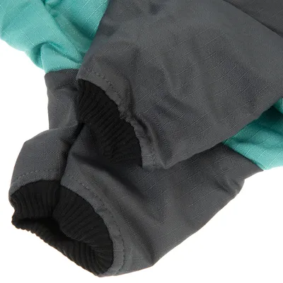 Dettaglio di maniche in tessuto grigio e turchese con polsini elastici neri.