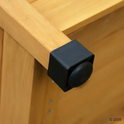 Puinen kulma, jossa musta muovinen suojakuppi ja pyöreä pääty. Näkyvissä metalliruuveja puupinnassa.