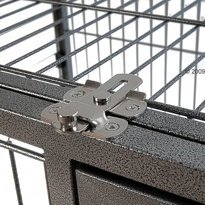 Метална ключалка на врата на клетка от метални решетки, закрепена с четири винта. Видима е част от конструкцията на клетката.