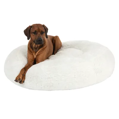 Hond ligt op een rond, wit, pluizig bed. Producttoepassing wordt getoond.