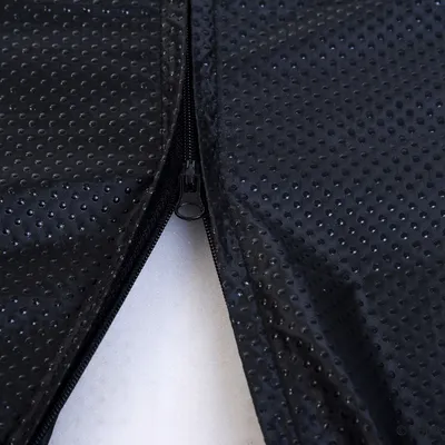 Gros plan sur une fermeture éclair noire sur tissu synthétique noir à surface antidérapante avec picots. Partie intérieure blanche visible sous la fermeture.