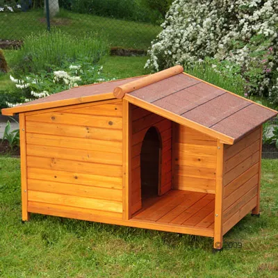Hundkoja i trä med öppning framtill och tak av bruna plattor, placerad på gräsmatta utomhus.